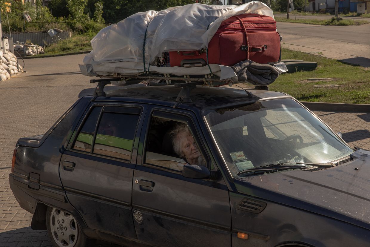 An elderly woman sits in a car loaded with items of luggage after she and her relatives fled from Toretsk by car, in the town of Kostyantynivka, eastern Donetsk Oblast, on June 22, 2024